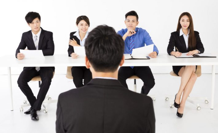 Business people interviewing young businessman in office