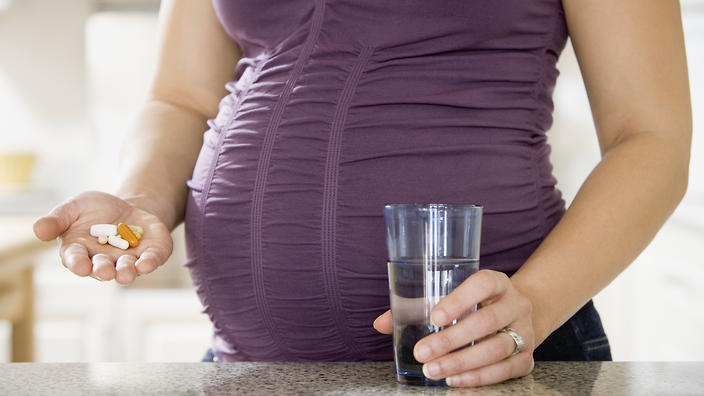 pregnant woman taking a pill