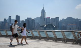 A-couple-walk-on-Avenue-of-Stars-with-the-Hong-Kong-island-skyline-on-the-background