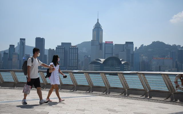 A-couple-walk-on-Avenue-of-Stars-with-the-Hong-Kong-island-skyline-on-the-background