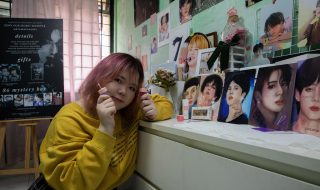 Ms Ng Kwok Ching poses with the BTS portraits she drew and her Loveholic Beauty cosmetics