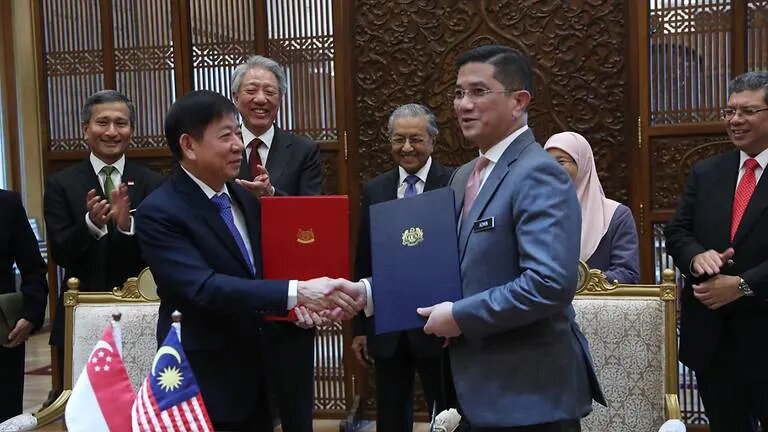 Singapore Transport Minister Khaw Boon Wan (left) and Malaysian Economic Affairs Minister Azmin Ali exchange documents in Putrajaya on Sep 5, 2018