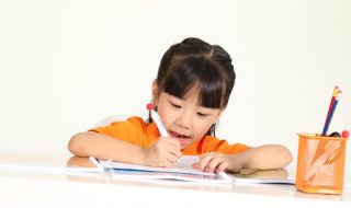 an asian child writing on a desk