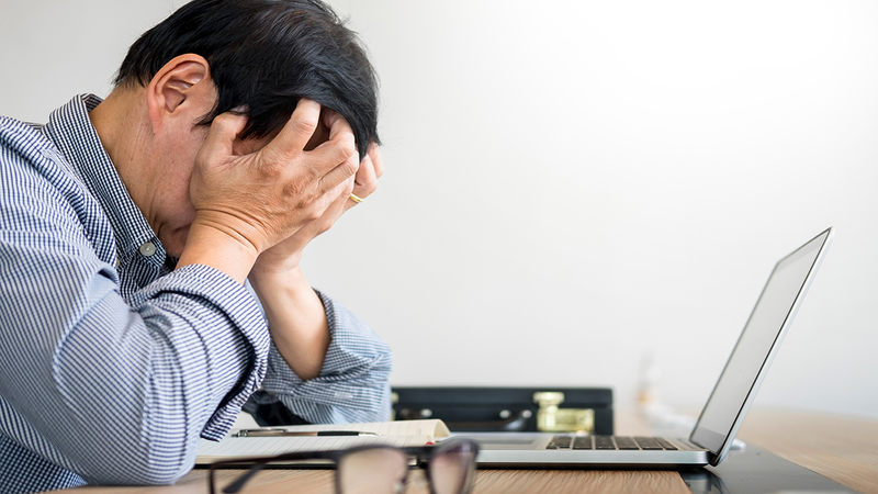 a stressed man in front of a laptop