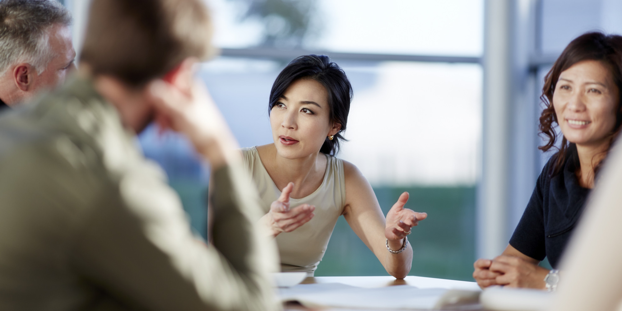 an asian woman asking questions at a business meeting