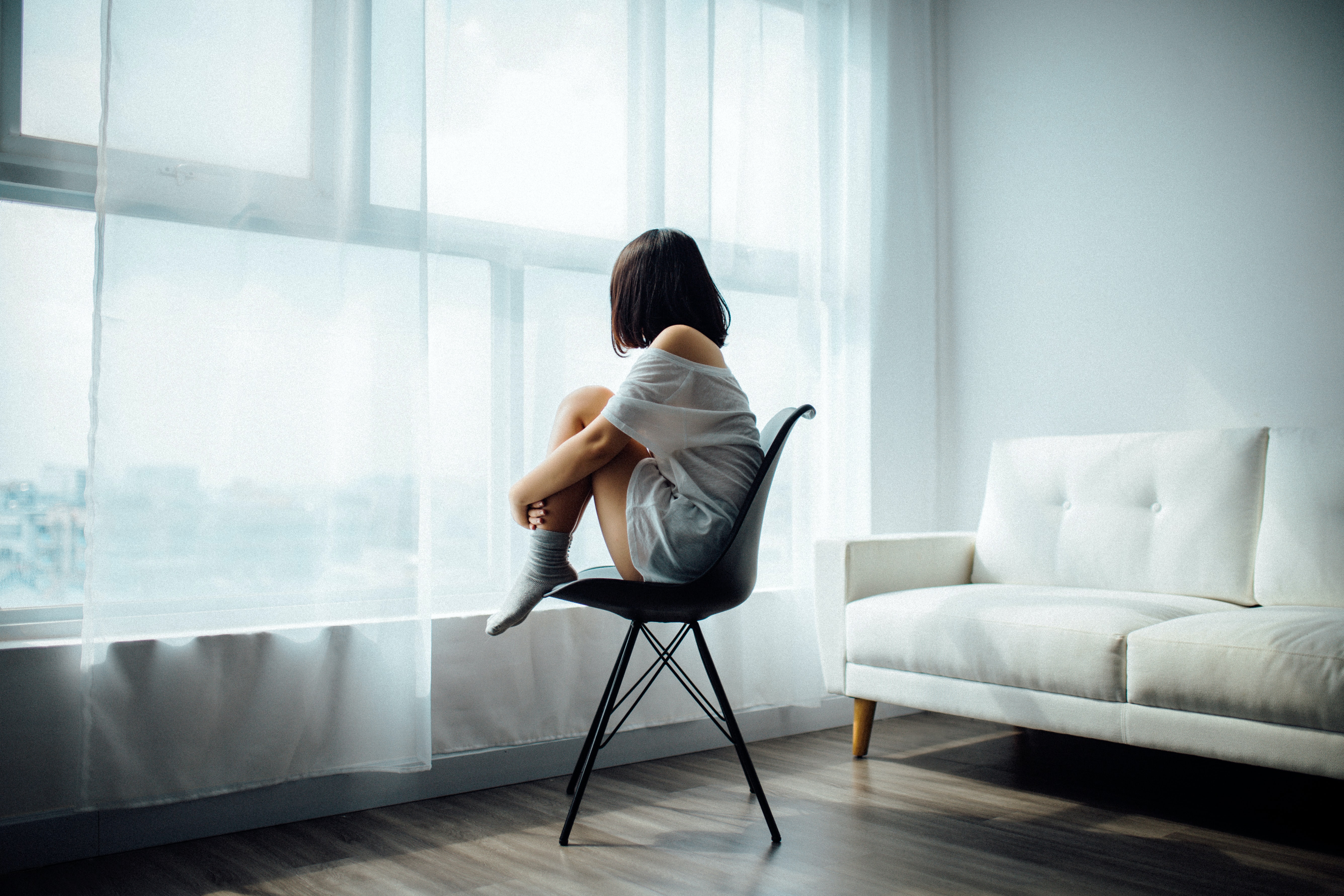 a woman sitting on a chair facing the window