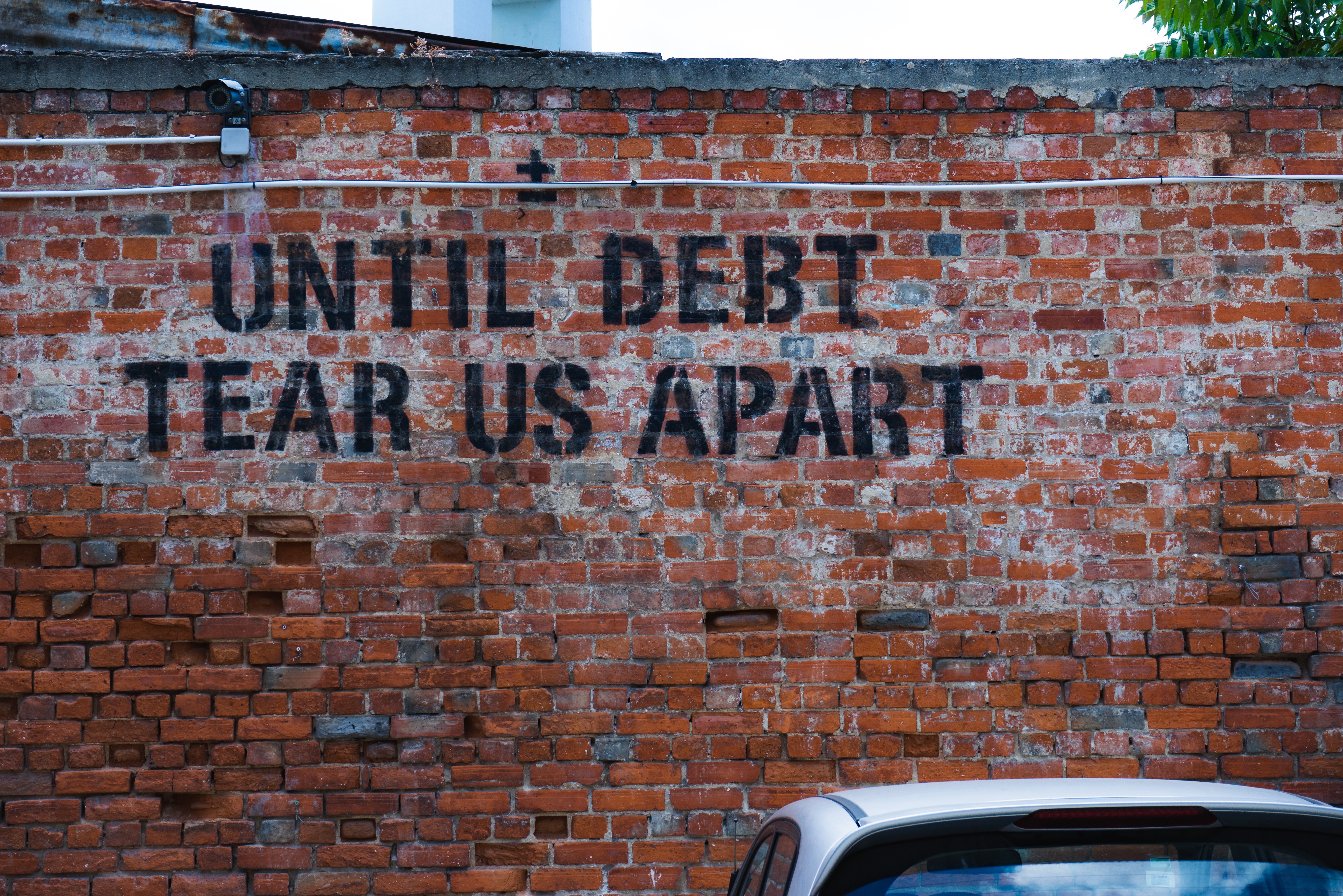 until debt tear us apart graffiti on a brick wall