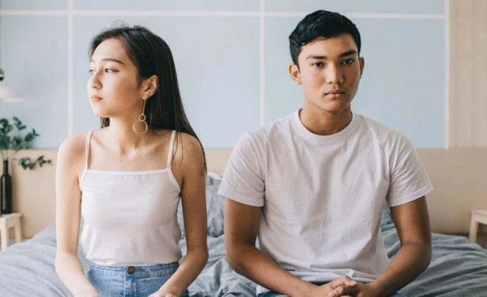 young-couple-sitting-on-their-bed