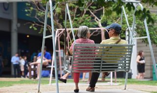 two elderly persons sitting on a swing