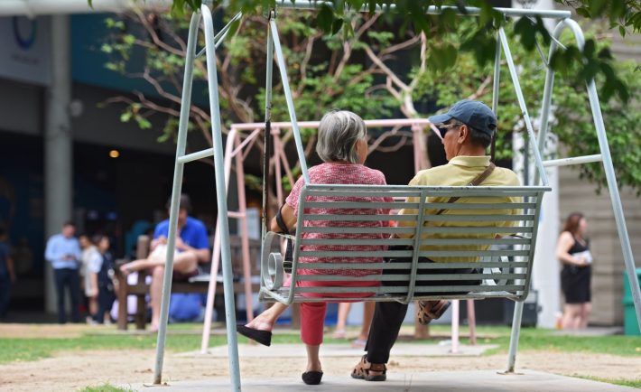 two elderly persons sitting on a swing