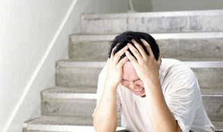 a stressed asian man sitting by the staircase