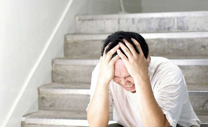 a stressed asian man sitting by the staircase