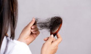 a woman looking at her hair loss on a comb