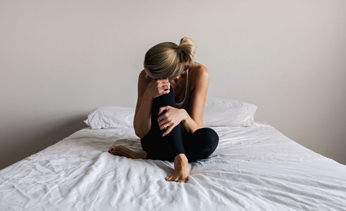 a depressed woman sitting on the bed