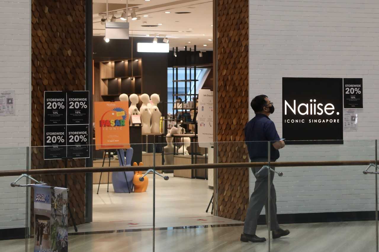 a man walking past the deserted Naiise outlet at Jewel