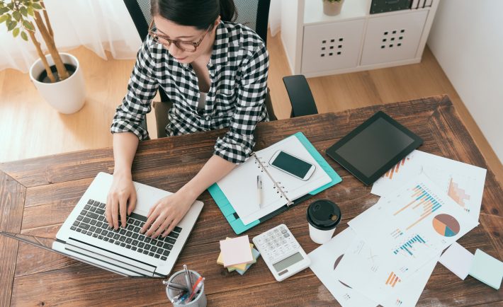 a woman working at home with a table filled with documents