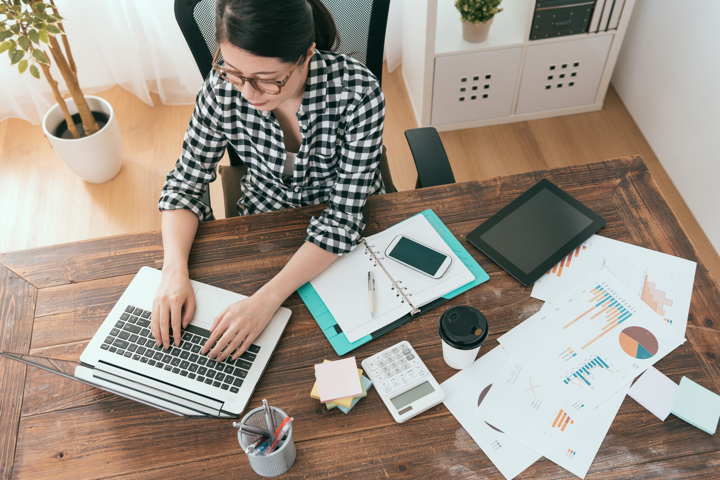 a woman working at home with a table filled with documents