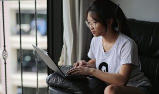an asian woman using her laptop on a sofa