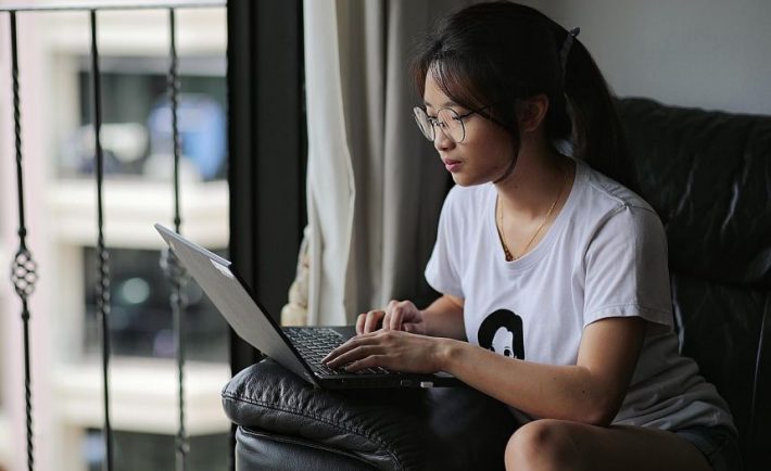 an asian woman using her laptop on a sofa