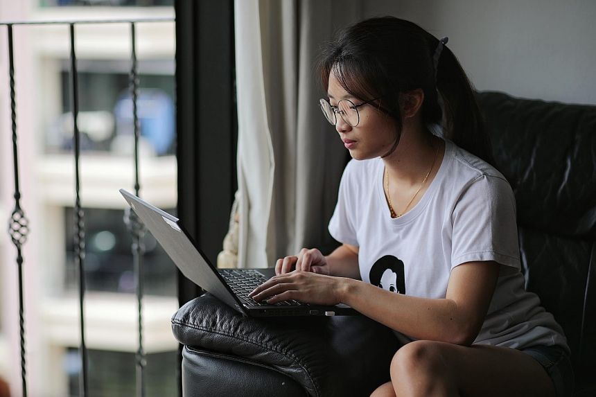 an asian woman using her laptop on a sofa