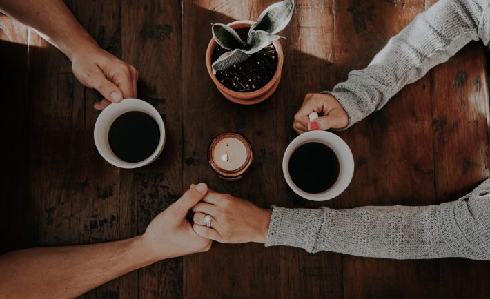 a couple drinking coffee and holding hands