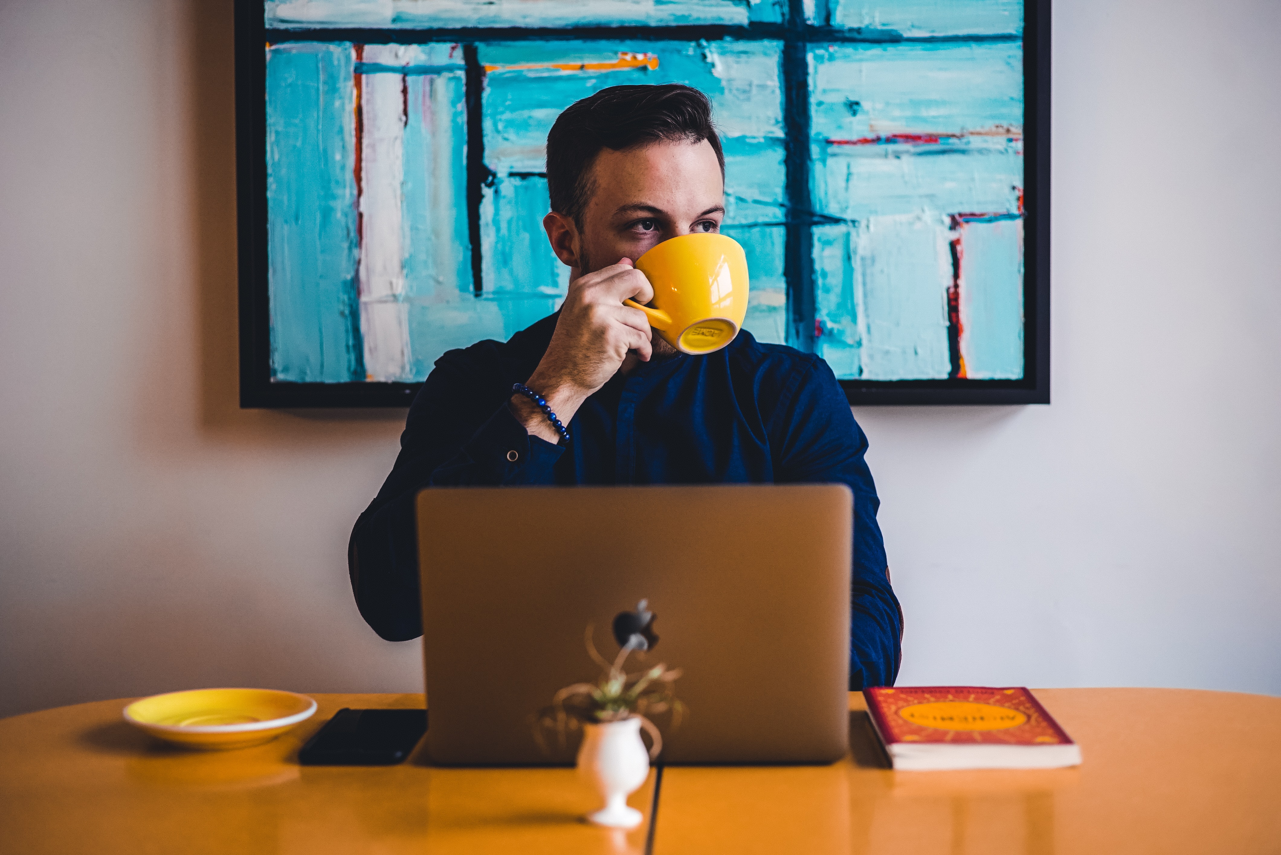 a man drinking coffee in front of his laptop