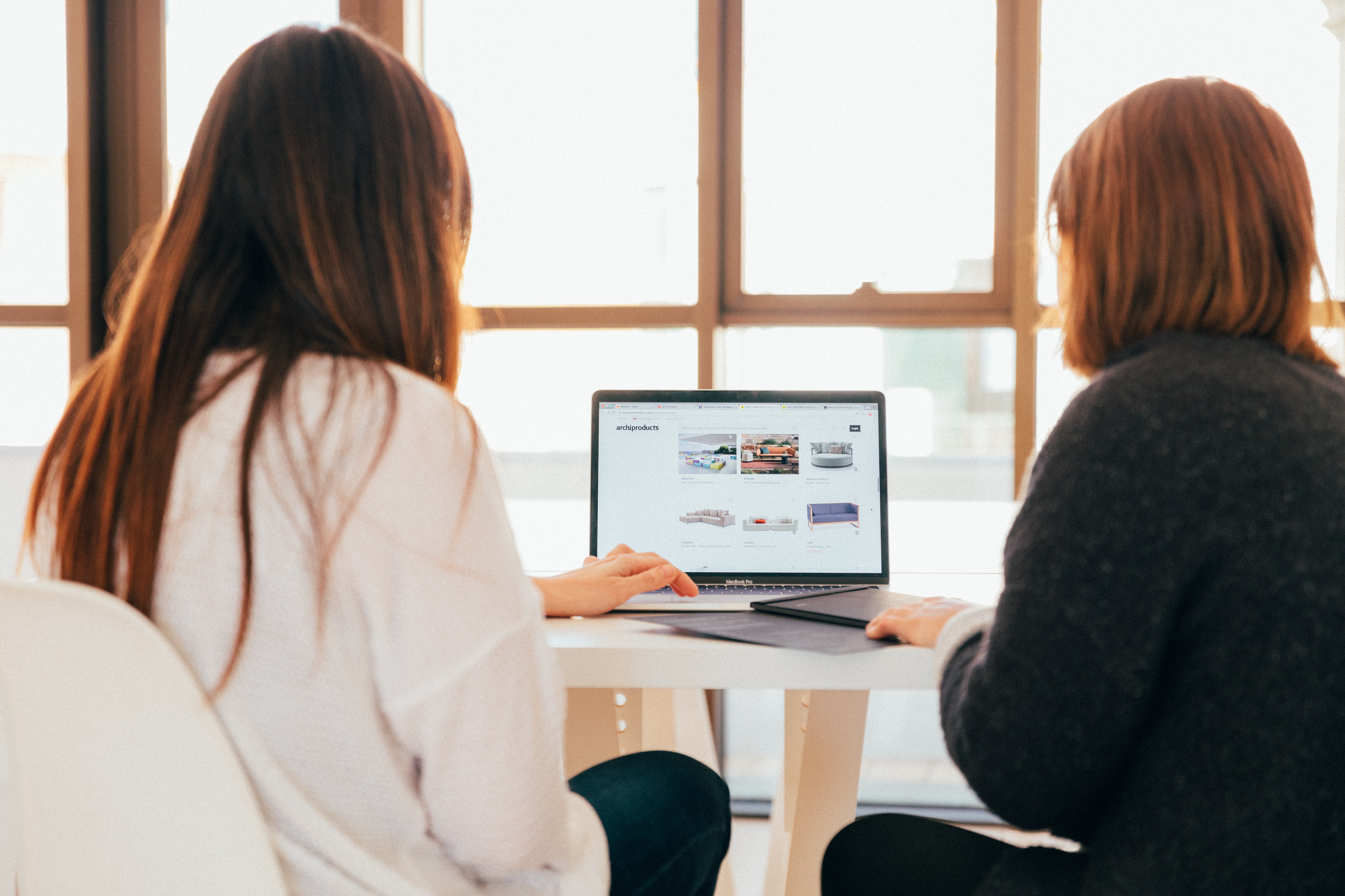 two women talking while using the laptop