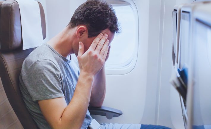 Man holding his head on the plane