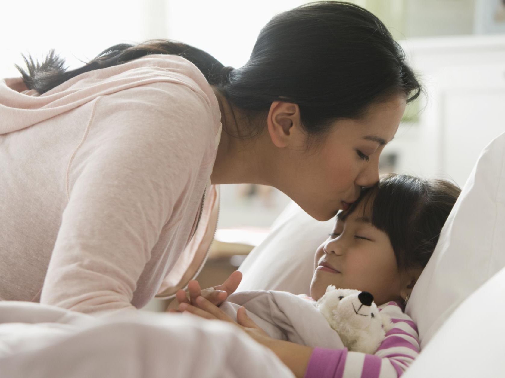 a mother kissing her daughter on the forehead