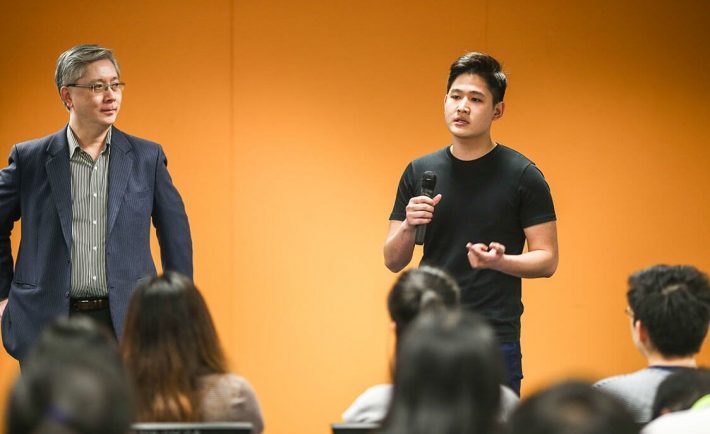 a young Asian man speaking publicly