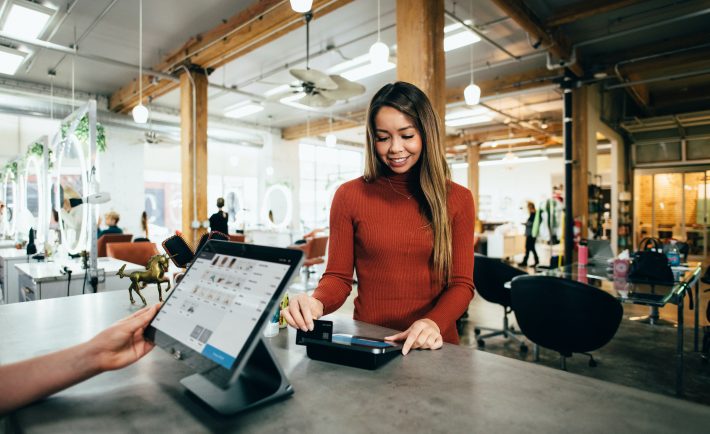 a woman swiping her credit card in-store