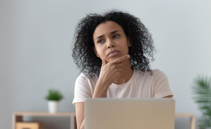 a woman thinking in front of her laptop