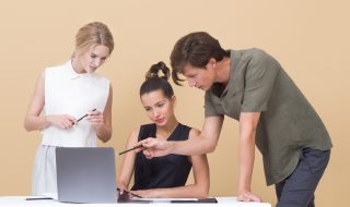 a young team of three discussing in front of the laptop