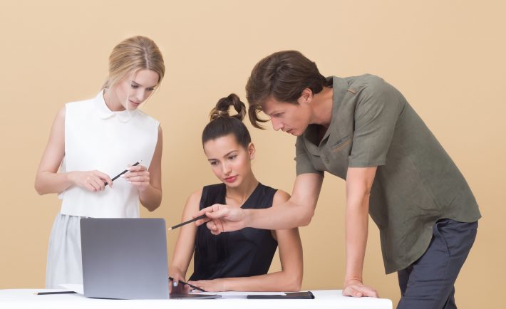 a young team of three discussing in front of the laptop