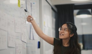 a lady presenting in front of a whiteboard