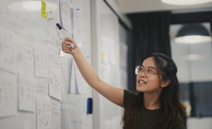 a lady presenting in front of a whiteboard