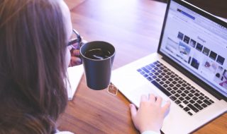 a lady drinking tea while using her laptop