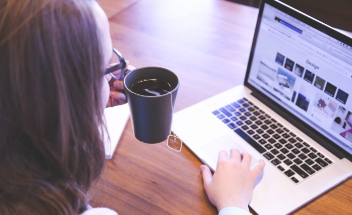 a lady drinking tea while using her laptop