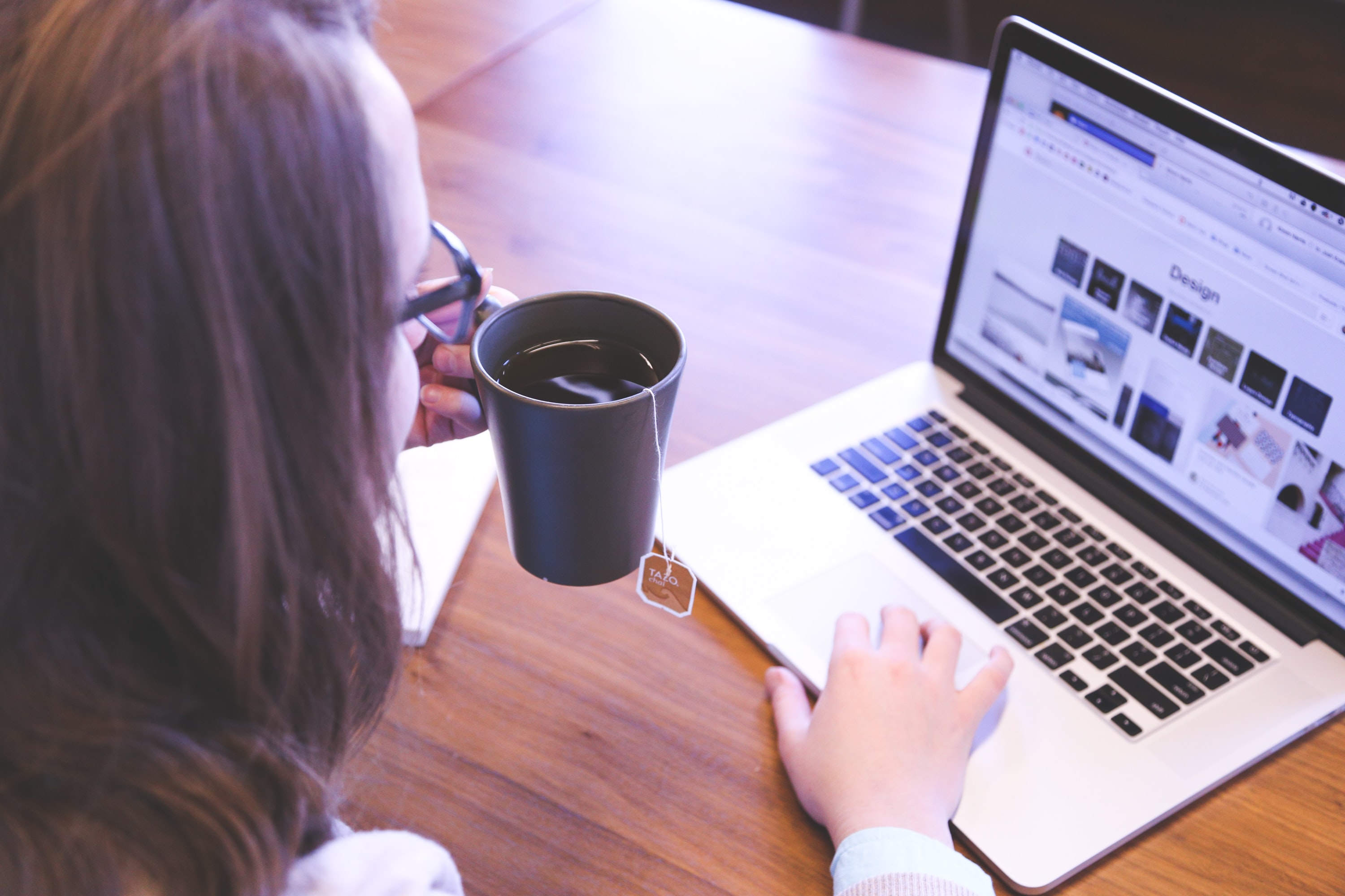 a lady drinking tea while using her laptop