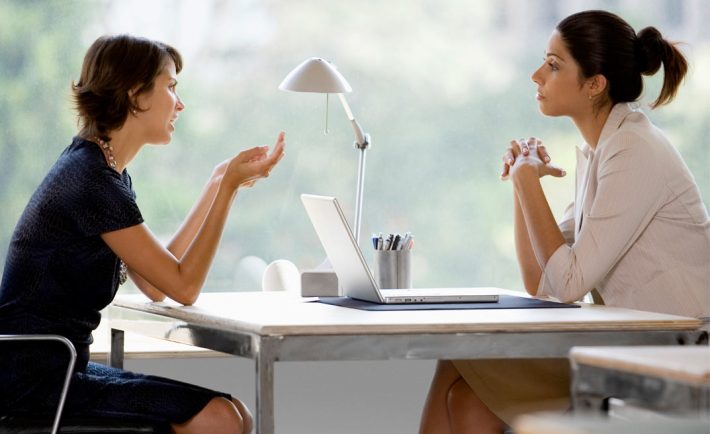 two female coworkers have a serious conversation