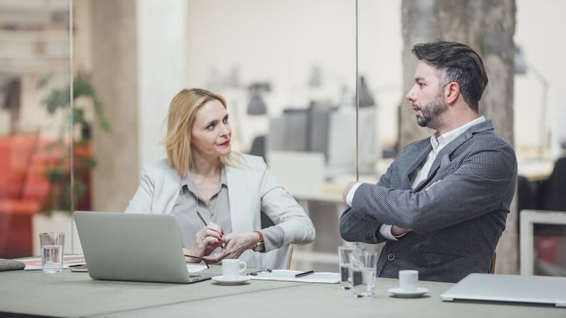 a man crossing arms during a meeting with his female colleague