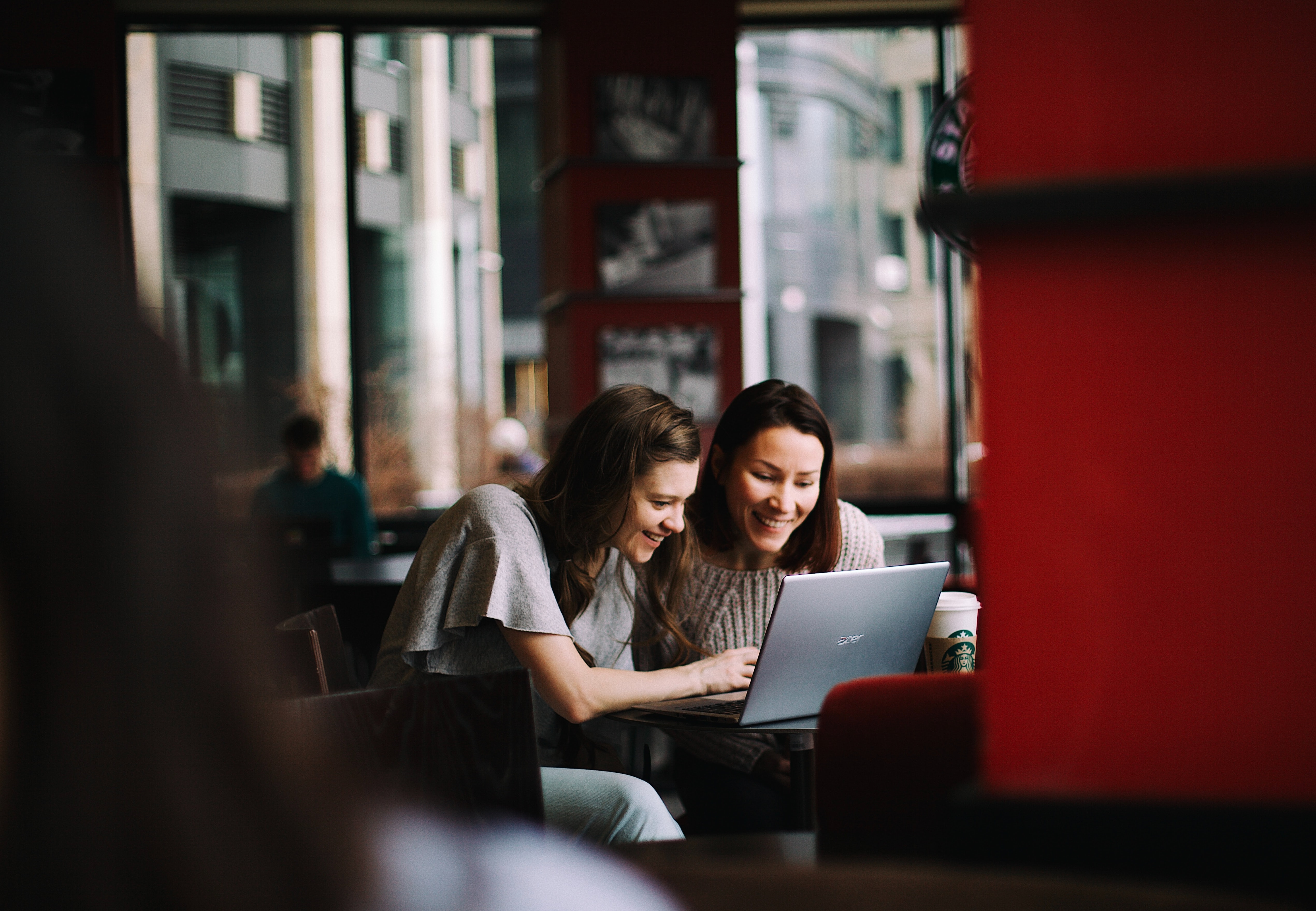 two female coworkers looking at a laptop in a cafe