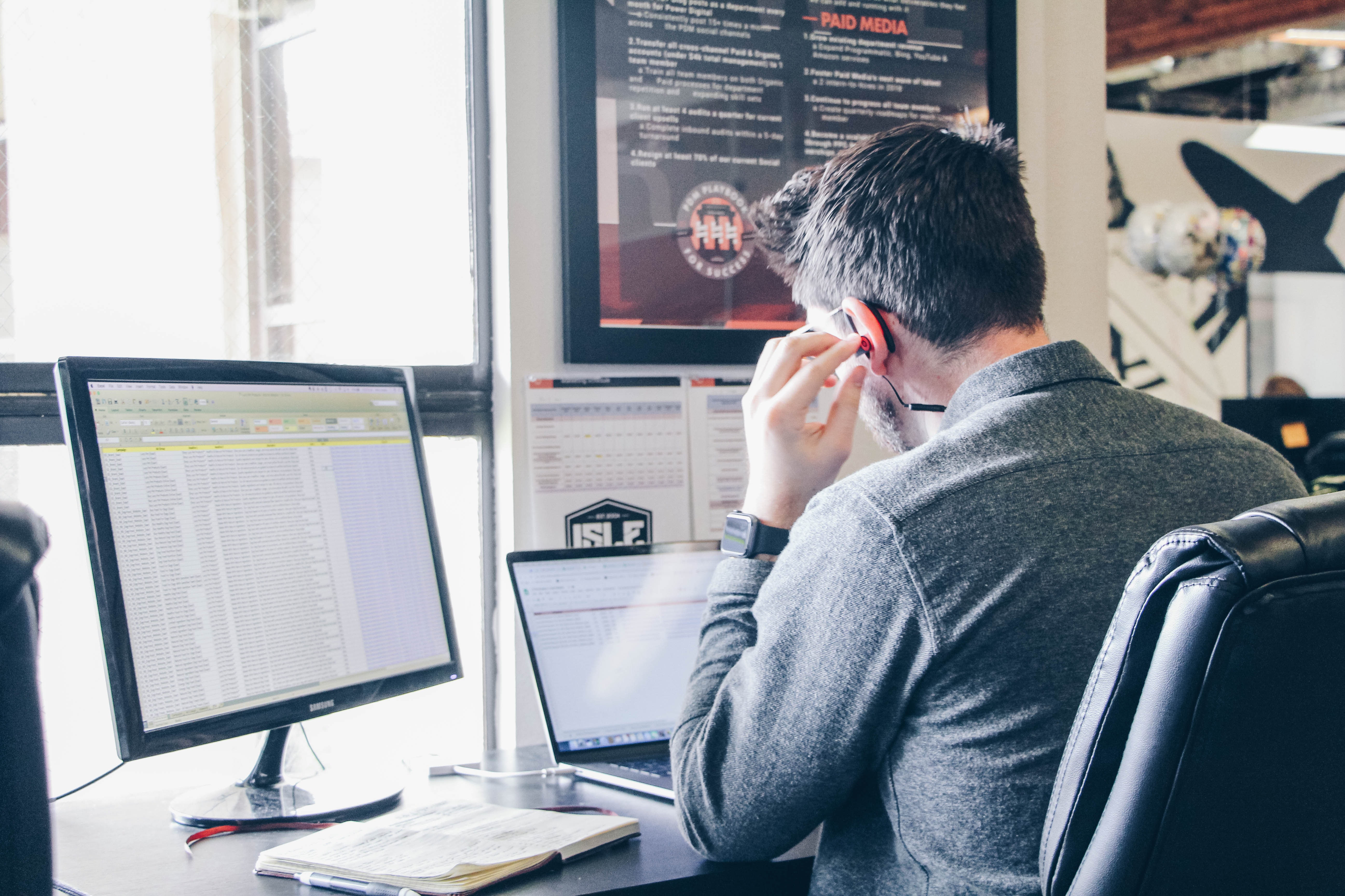 man listening to music as he works at his desk on a laptop