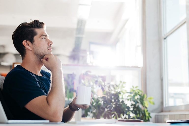 man in deep thought while holding a coffee mug