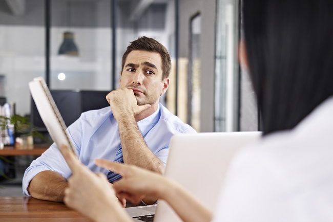 man raising eyebrows in a conversation with his coworker