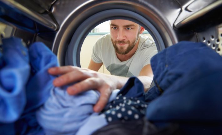 man loading his clothes in a washer
