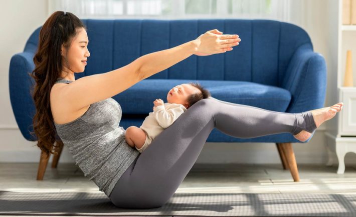 woman holding a yoga pose with baby sleeping on her thighs