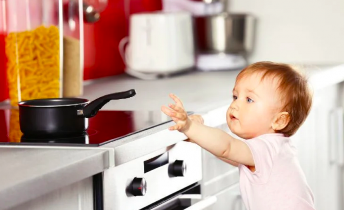 baby reaching out to a pot in the kitchen