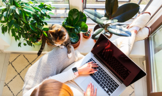 woman working on a laptop with a cat by her side