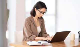 woman in spectacles working on her laptop